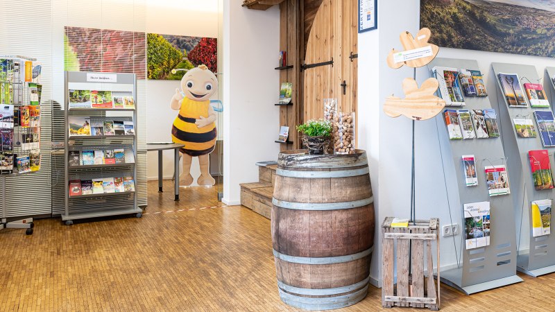 Innenansicht einer Tourist-Info mit Prospektständern, einem Weinfass und einer Bienenfigur. Helle, einladende Atmosphäre., © Remstal Tourismus, Peter Schuster