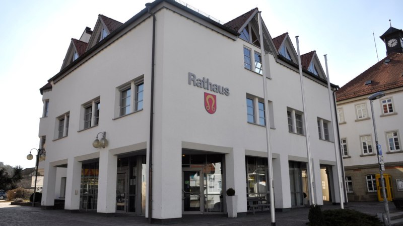 Das Nufringer Rathaus mit weißer Fassade und roten Dächern, zwei Eingängen und einem Wappen an der Wand., © Natur.Nah. Schönbuch & Heckengäu Das Nufringer Rathaus mit weißer Fassade und roten Dächern, zwei Eingängen und einem Wappen an der Wand., © Natur.Nah. Schönbuch & Heckengäu