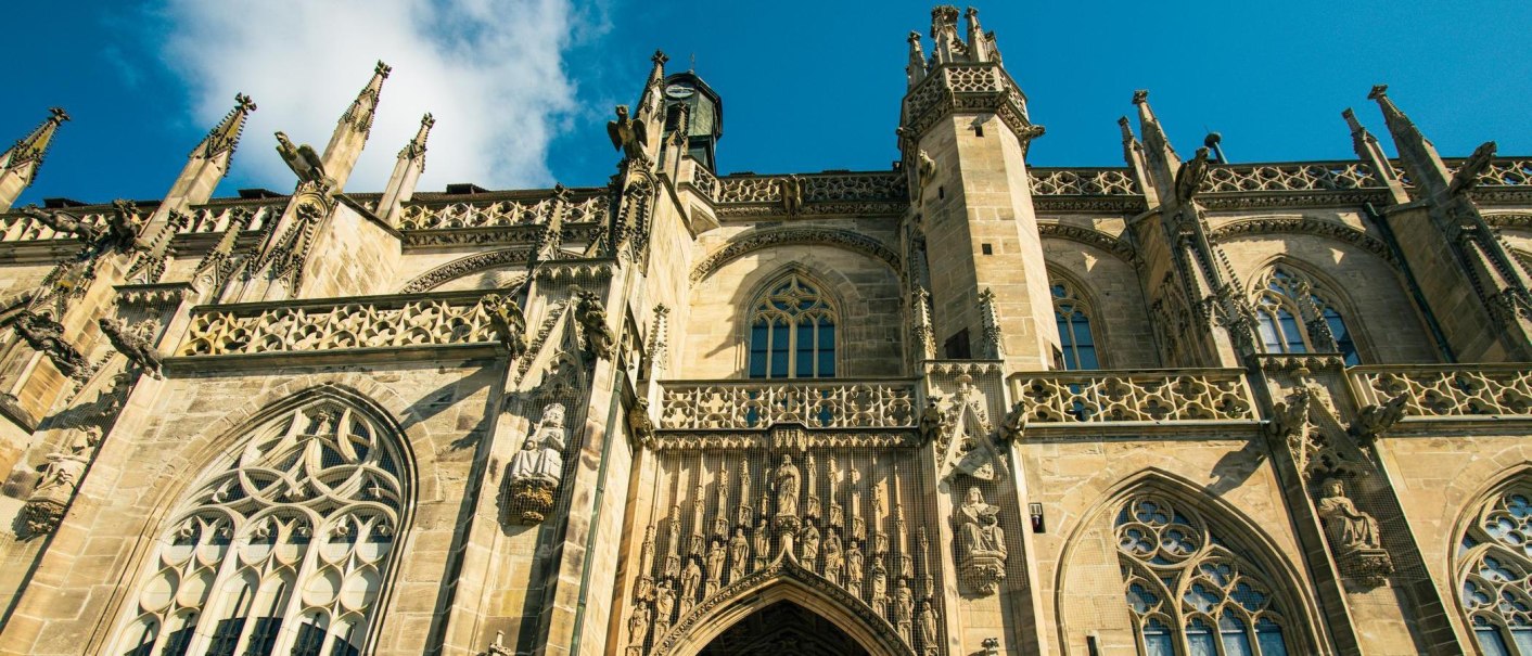 Detailreiche gotische Fassade des Heilig-Kreuz-Münsters in Schwäbisch Gmünd, verziert mit Statuen und filigranen Steinmetzarbeiten unter blauem Himmel., © Stuttgart-Marketing GmbH, Sarah Schmid Detailreiche gotische Fassade des Heilig-Kreuz-Münsters in Schwäbisch Gmünd, verziert mit Statuen und filigranen Steinmetzarbeiten unter blauem Himmel., © Stuttgart-Marketing GmbH, Sarah Schmid