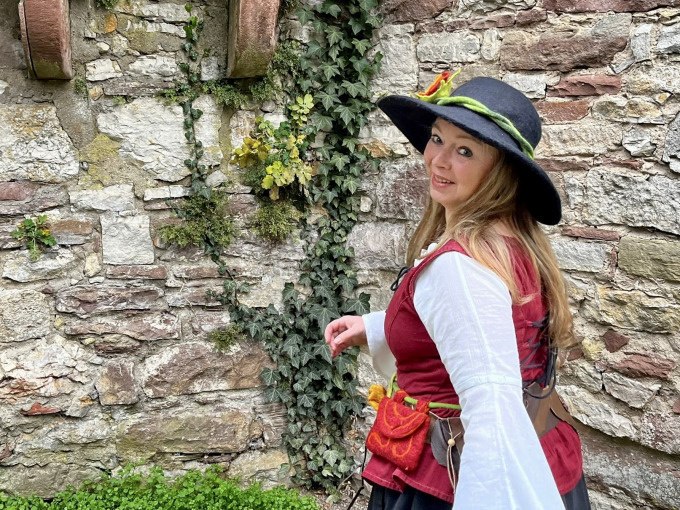 Frau in mittelalterlicher Kleidung mit Hut lächelt vor einer efeubewachsenen Steinmauer., © Stadtverwaltung Weil der Stadt Frau in mittelalterlicher Kleidung mit Hut lächelt vor einer efeubewachsenen Steinmauer., © Stadtverwaltung Weil der Stadt