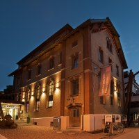 Das Mauerwerk in Herrenberg bei Dämmerung, ein beleuchtetes Backsteingebäude mit großen Fenstern und einem Banner. Der Himmel ist dunkelblau., © Stadt Herrenberg Das Mauerwerk in Herrenberg bei Dämmerung, ein beleuchtetes Backsteingebäude mit großen Fenstern und einem Banner. Der Himmel ist dunkelblau., © Stadt Herrenberg
