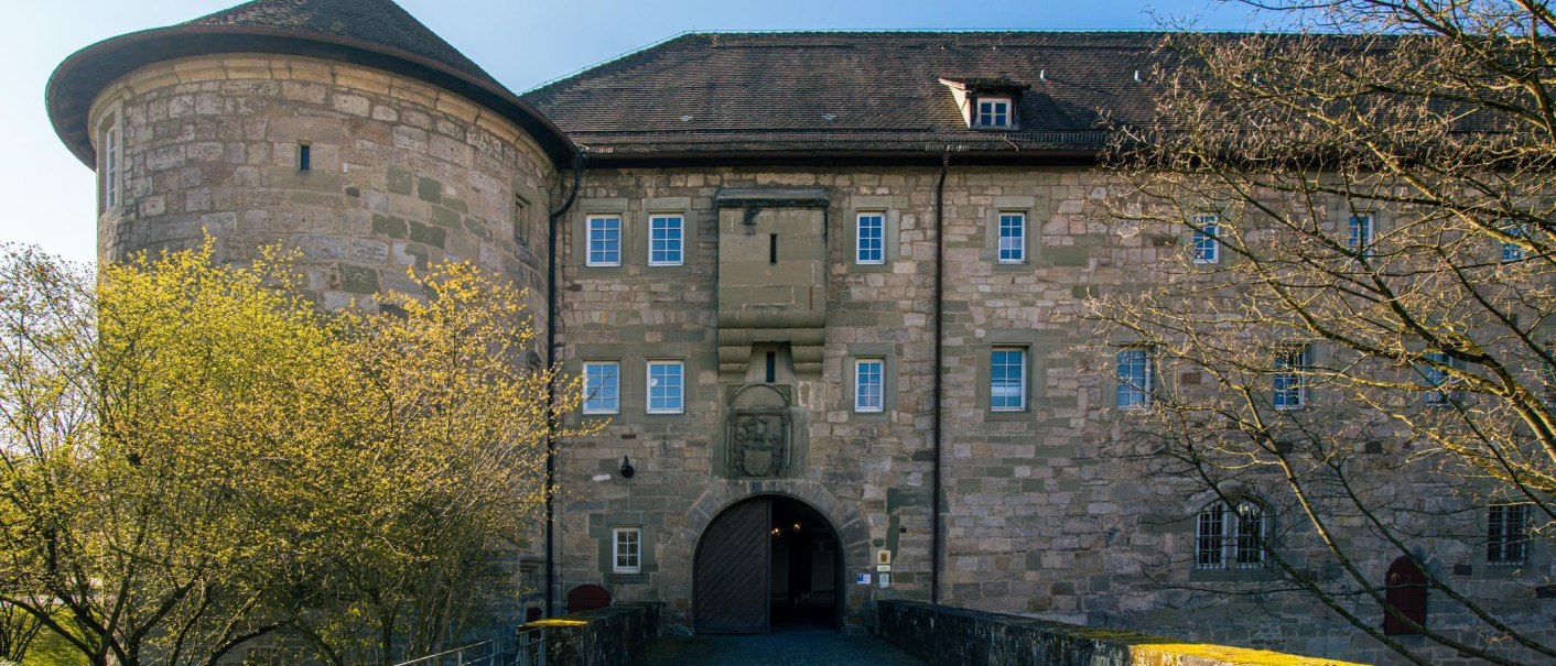 Das Burgschloss Schorndorf zeigt eine beeindruckende Fassade mit einem runden Turm und steinernen Mauern, umgeben von Bäumen im Frühling., © Stuttgart-Marketing GmbH, Sarah Schmid Das Burgschloss Schorndorf zeigt eine beeindruckende Fassade mit einem runden Turm und steinernen Mauern, umgeben von Bäumen im Frühling., © Stuttgart-Marketing GmbH, Sarah Schmid