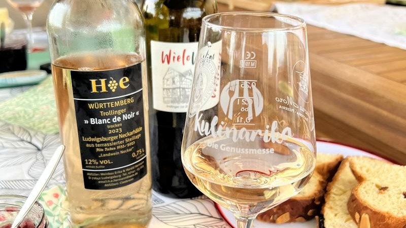 Zwei Weinflaschen und ein Glas Wei&szlig;wein stehen auf einem Tisch mit Geb&auml;ck. Im Hintergrund sind weitere Getr&auml;nke und ein Holzbrett zu sehen., &copy; Quelle: Manuela Priber; Tourismus & Events Ludwigsburg