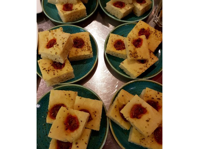 Kleine Focaccia-Stücke mit Tomaten und Kräutern auf mehreren grünen Tellern angerichtet., © Kultweine-Kochwelten-Kunstücke - Kochschule Sonja Lenz Kleine Focaccia-Stücke mit Tomaten und Kräutern auf mehreren grünen Tellern angerichtet., © Kultweine-Kochwelten-Kunstücke - Kochschule Sonja Lenz