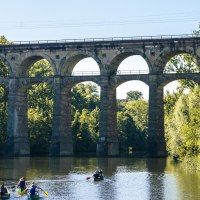 Viadukt in Bietigheim-Bissingen über einem Fluss. Mehrere Kanufahrer paddeln unter der Brücke. Umgeben von grünen Bäumen und klarem Himmel., © Stuttgart Marketing GmbH, Sarah Schmid