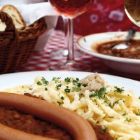 Ein Teller mit Linsen, Spätzle und Würstchen auf einem rot-weiß karierten Tischtuch. Im Hintergrund ein Brotkorb und ein Glas Wein., © Stuttgart-Marketing GmbH