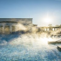 Dampf steigt aus dem Außenpool der Böblingen Mineraltherme auf, während die Sonne am klaren Himmel scheint., © SMG, Sarah Schmid