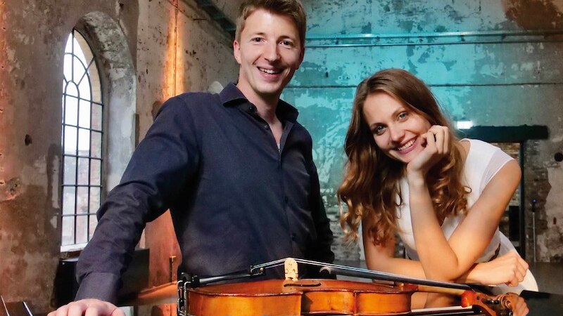 Ein Mann und eine Frau lächeln in einem rustikalen Raum. Eine Geige liegt auf einem Tisch vor ihnen. Der Raum hat große Fenster und eine abgenutzte Wand., © Schönblick gemeinnützige GmbH Ein Mann und eine Frau lächeln in einem rustikalen Raum. Eine Geige liegt auf einem Tisch vor ihnen. Der Raum hat große Fenster und eine abgenutzte Wand., © Schönblick gemeinnützige GmbH