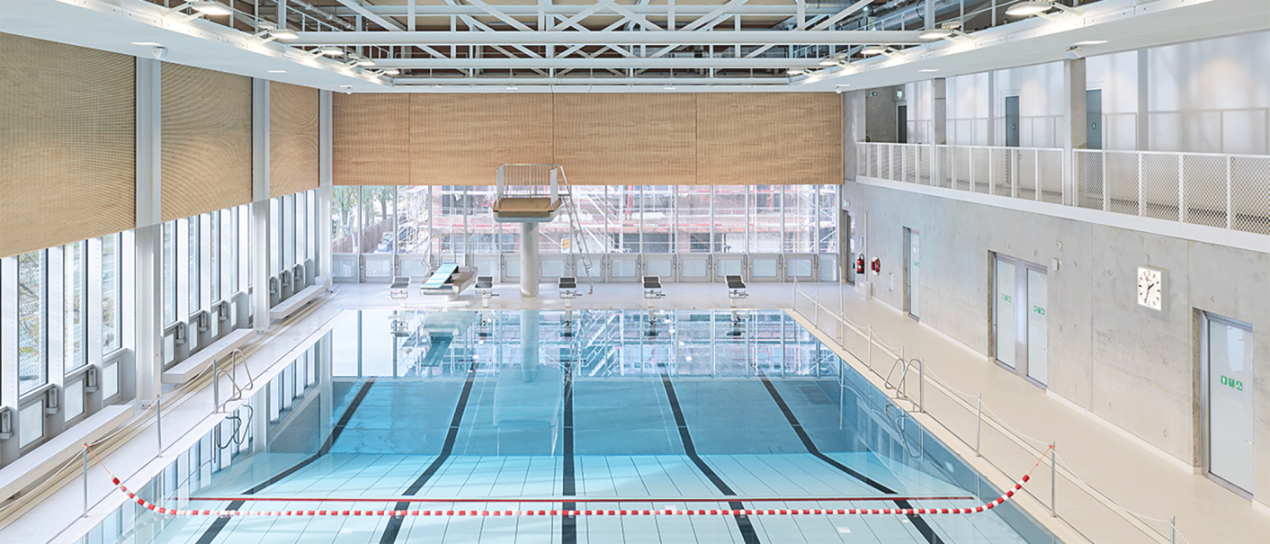 Modernes Schwimmbad mit Sprungturm, Startblöcken und großen Fenstern. Helle, offene Architektur mit Sicht auf Bauarbeiten draußen., © Stuttgarter Bäder Modernes Schwimmbad mit Sprungturm, Startblöcken und großen Fenstern. Helle, offene Architektur mit Sicht auf Bauarbeiten draußen., © Stuttgarter Bäder