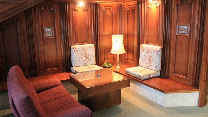 Gemütliche Sitzecke mit Holzwänden, floral gemusterten Kissen, Tisch und Lampe. Ein Telefon steht auf dem Tisch., © Hotel Spahr