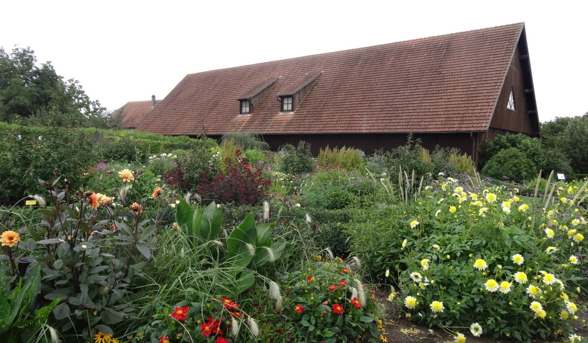 Bunter Blumengarten vor einem traditionellen Bauernhaus mit rotem Ziegeldach und Holzwänden., © Nürtingen - Stuttgart-Marketing GmbH