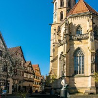Die Stadtkirche in Schorndorf mit ihrem markanten Turm steht neben traditionellen Fachwerkhäusern unter einem klaren blauen Himmel., © Stuttgart-Marketing GmbH, Sarah Schmid