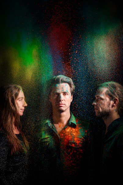 Drei Personen stehen vor einem dunklen Hintergrund, umgeben von buntem Farbpulver in Grün, Rot und Blau., © Konzertkreis Triangel Compagnia Compostelli e.V. Drei Personen stehen vor einem dunklen Hintergrund, umgeben von buntem Farbpulver in Grün, Rot und Blau., © Konzertkreis Triangel Compagnia Compostelli e.V.