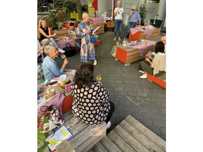 Menschen sitzen auf Holzb&auml;nken und genie&szlig;en ein gemeinsames Picknick in einer st&auml;dtischen Umgebung. Es herrscht eine entspannte und gesellige Atmosph&auml;re., &copy; Eigenbetrieb Tourismus und Citymanagement Schorndorf