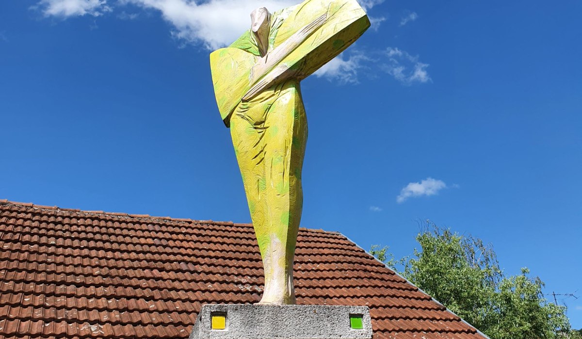Skulptur einer abstrakten Frauenfigur von Wolfgang Thiel im Kulturpark Dettinger, auf einem Sockel vor einem Gebäude mit Ziegeldach, blauer Himmel im Hintergrund., © Kulturamt Plochingen