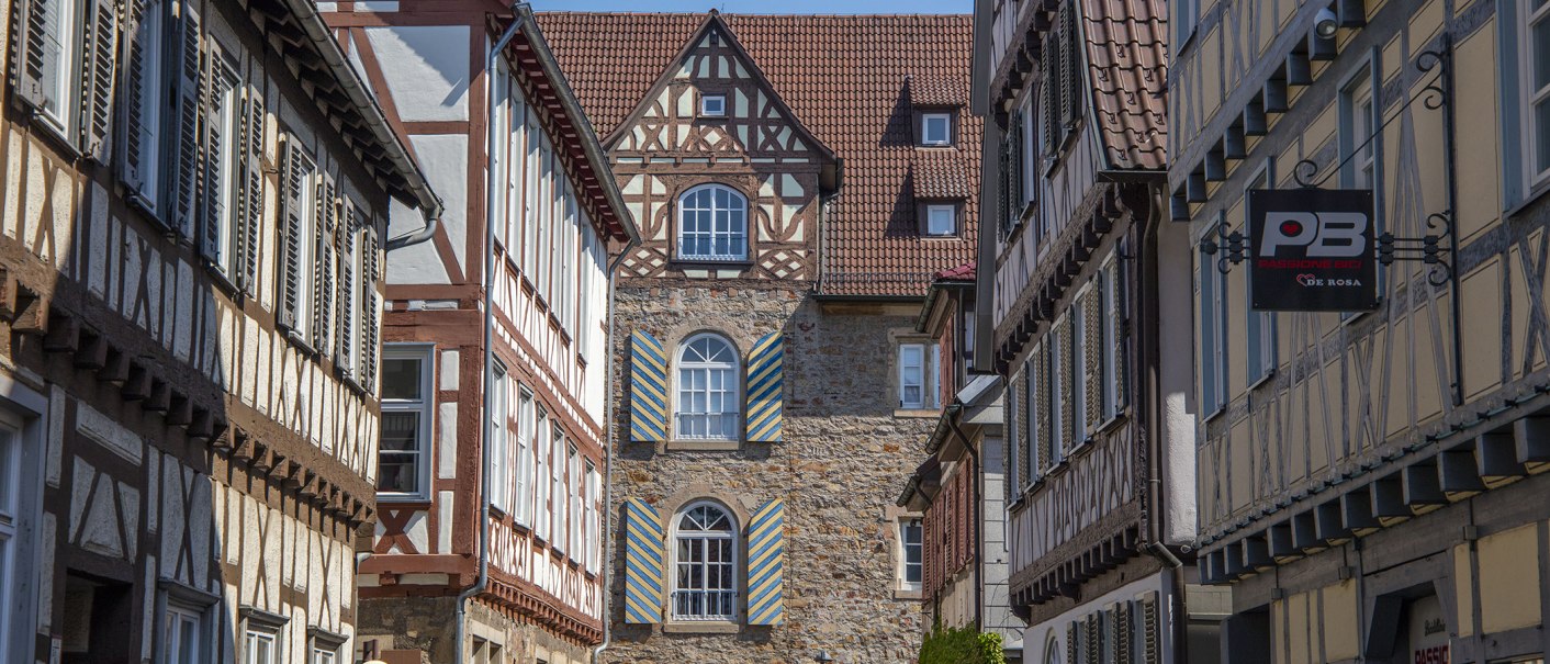 Fachwerkhäuser säumen eine schmale Gasse in Kirchheim unter Teck. Ein Schild mit der Aufschrift 'Passione Bici' ist sichtbar., © Achim Mende Fachwerkhäuser säumen eine schmale Gasse in Kirchheim unter Teck. Ein Schild mit der Aufschrift 'Passione Bici' ist sichtbar., © Achim Mende