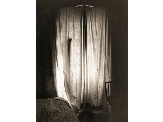 Ein Raum mit einem zugezogenen Vorhang, durch den Licht f&auml;llt. Ein Bett und ein Stuhl sind im Schatten sichtbar., &copy; Kunsthalle G&ouml;ppingen