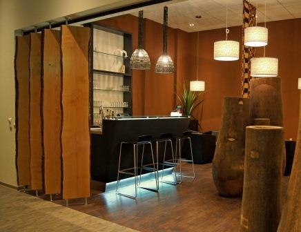 Moderne Bar mit Holzdekor, schwarzen Hockern und stilvollen Lampen. Die Einrichtung wirkt warm und einladend., &copy; TOMAS