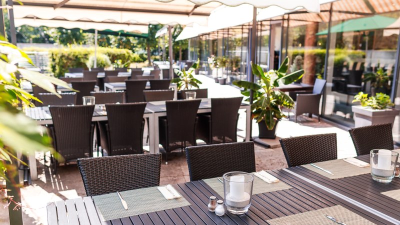 Restaurantterrasse mit gedeckten Tischen und Stühlen unter Sonnenschirmen, umgeben von Pflanzen., © PLAZA Hotelgroup GmbH