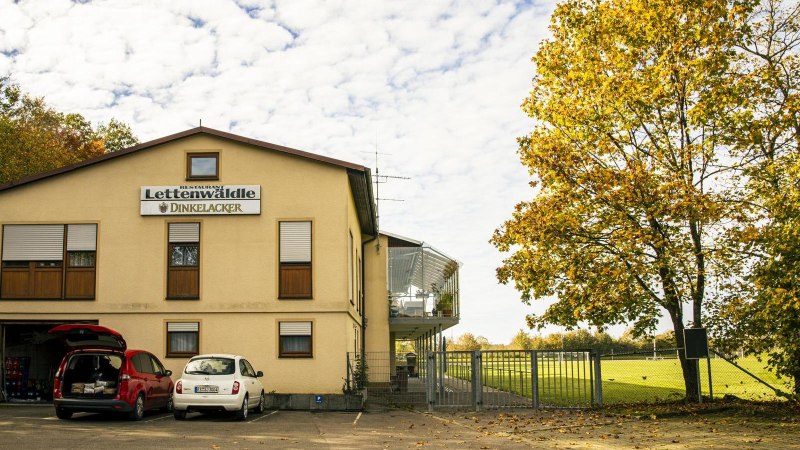 Sportheim Lettenw&auml;ldle mit geparkten Autos, umgeben von herbstlichen B&auml;umen und einem Sportplatz im Hintergrund., &copy; Stuttgart Marketing GmbH, Sarah Schmid