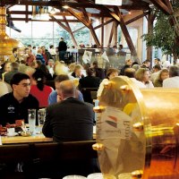 Belebtes Brauhaus mit vielen Menschen an Tischen, Kupferkessel im Hintergrund, Holzbalken und gro&szlig;e Fenster., &copy; SMG