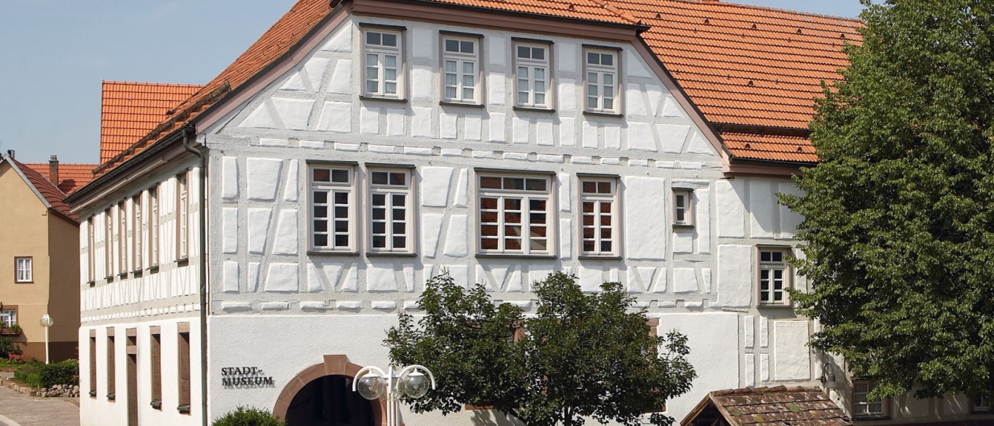 Fachwerkgebäude des Stadtmuseums Gerlingen mit rotem Ziegeldach, Bäumen und kleinem Brunnen im Vordergrund., © Stadtmuseum Gerlingen Fachwerkgebäude des Stadtmuseums Gerlingen mit rotem Ziegeldach, Bäumen und kleinem Brunnen im Vordergrund., © Stadtmuseum Gerlingen