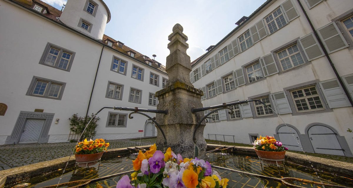 Innenhof von Schloss Waldenbuch mit einem zentralen Brunnen, umgeben von historischen Gebäuden. Bunte Blumen schmücken den Brunnenrand., © Region Stuttgart Innenhof von Schloss Waldenbuch mit einem zentralen Brunnen, umgeben von historischen Gebäuden. Bunte Blumen schmücken den Brunnenrand., © Region Stuttgart