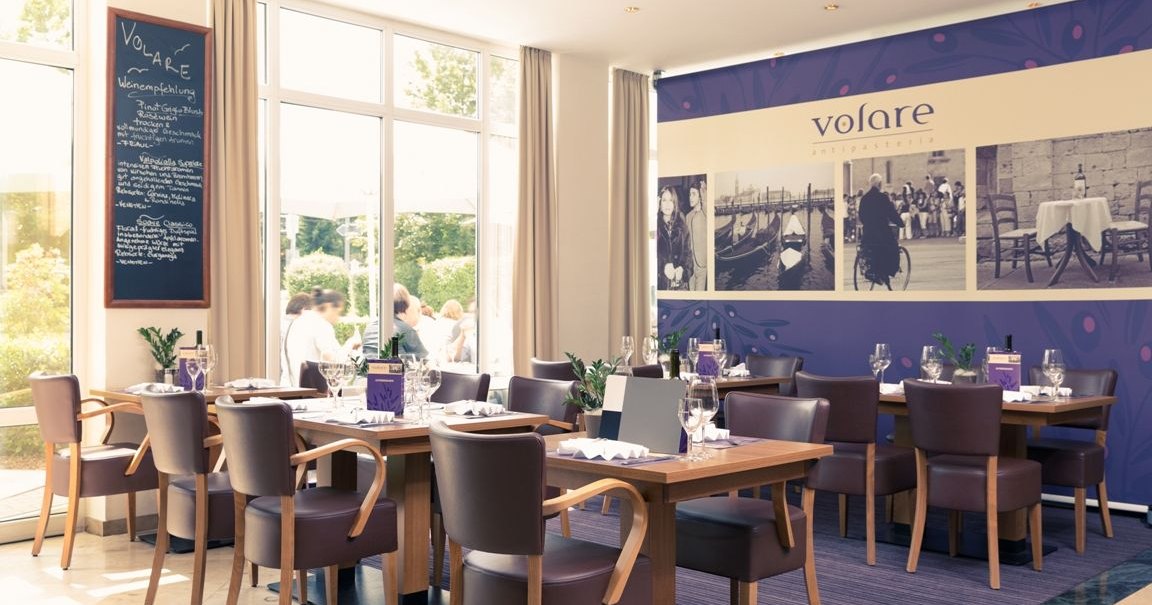 Eleganter Frühstücksbereich mit gedeckten Tischen, modernen Stühlen und großen Fenstern. An der Wand ein großes Bild mit 'Volare'-Schriftzug., © Mercure Hotel Stuttgart Gerlingen Eleganter Frühstücksbereich mit gedeckten Tischen, modernen Stühlen und großen Fenstern. An der Wand ein großes Bild mit 'Volare'-Schriftzug., © Mercure Hotel Stuttgart Gerlingen