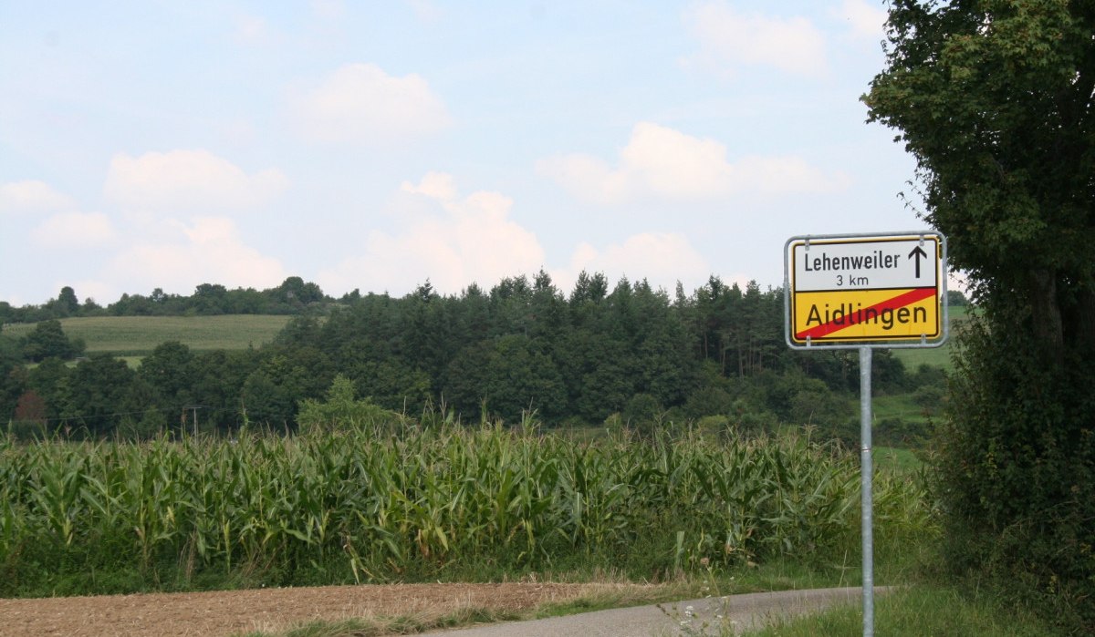 Straßenschild zeigt das Ende von Aidlingen und Richtung nach Lehenweiler. Umgebung mit Feldern und Bäumen, blauer Himmel im Hintergrund., © Natur.Nah. Schönbuch & Heckengäu Straßenschild zeigt das Ende von Aidlingen und Richtung nach Lehenweiler. Umgebung mit Feldern und Bäumen, blauer Himmel im Hintergrund., © Natur.Nah. Schönbuch & Heckengäu