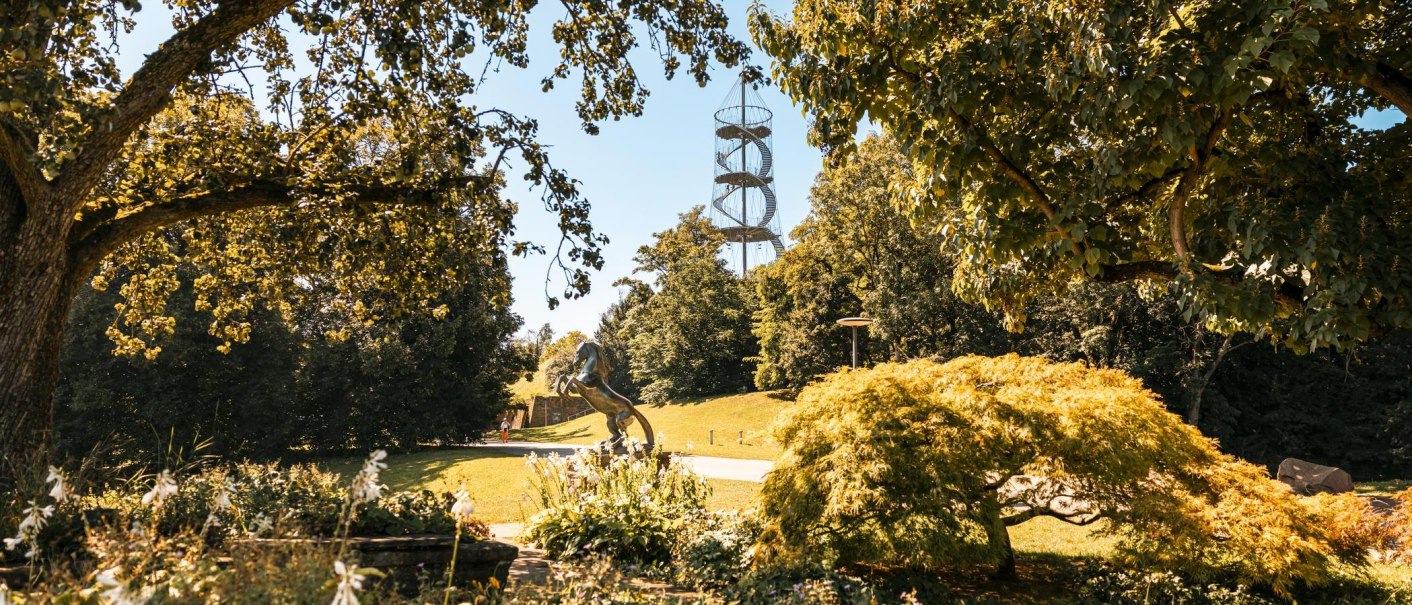 Ein gr&uuml;ner Park mit B&auml;umen, einer Pferdeskulptur und einem spiralf&ouml;rmigen Aussichtsturm im Hintergrund., &copy; Stuttgart-Marketing GmbH, Sarah Schmid