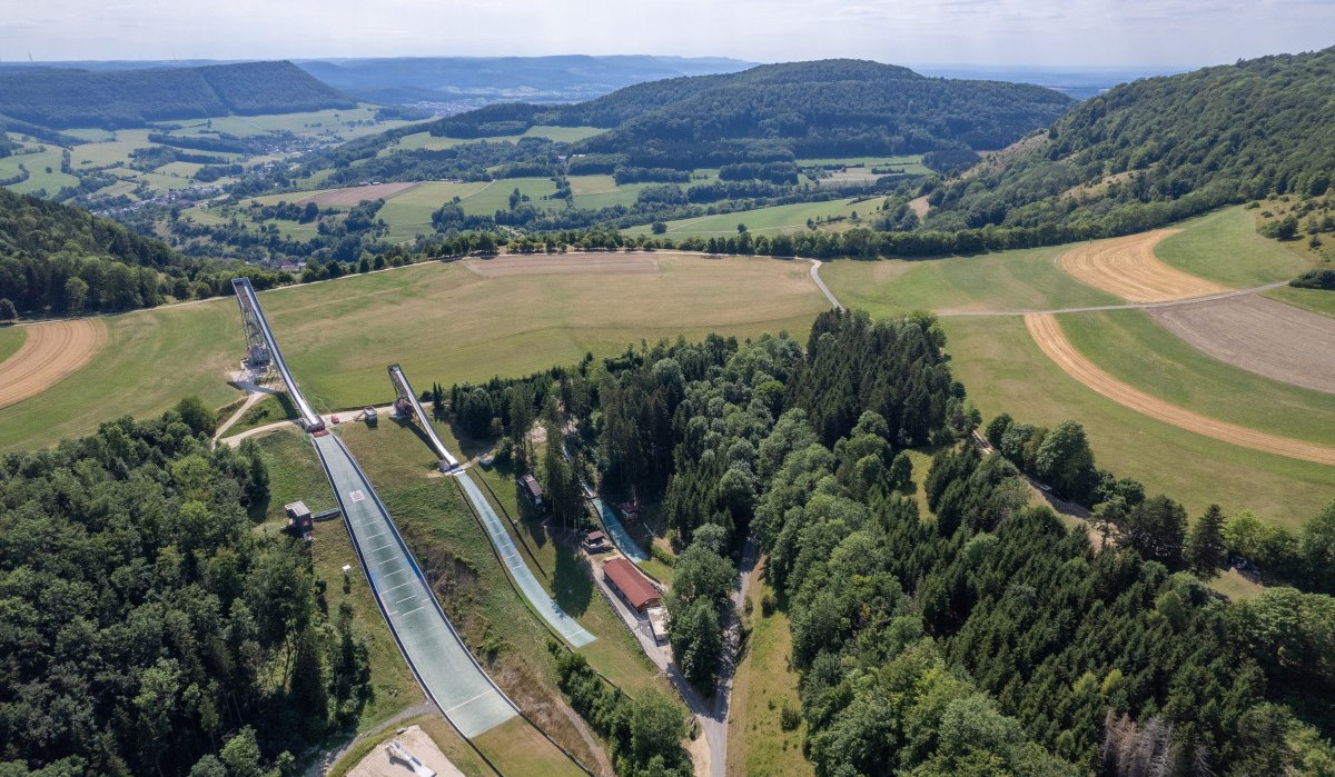 Luftaufnahme der Degenfelder Skisprungschanzen in einer grünen, hügeligen Landschaft mit Wäldern und Feldern., © Foto Thomas Zehnder