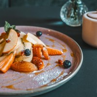 Ein Teller mit geschnittenen Fr&uuml;chten, Beeren und Sirup. Daneben eine Zuckerdose und ein Salzstreuer auf einem dunklen Tisch., &copy; Lupin, Stuttgart