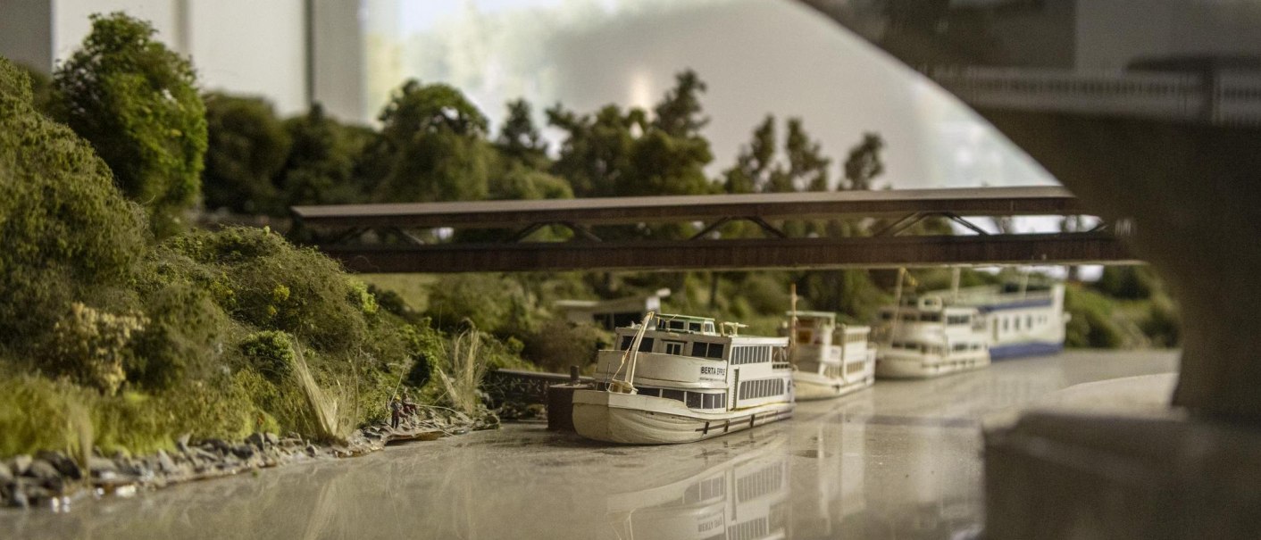 Miniaturmodell einer Flusslandschaft mit Brücke, Bäumen und mehreren Booten. Detailreiche Darstellung in einer Ausstellung., © Stuttgart-Marketing GmbH, Sarah Schmid