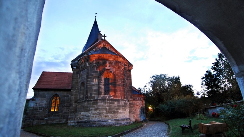 Die Stiftskirche Faurndau bei Dämmerung, umgeben von Bäumen und einem Kiesweg. Der Himmel ist leicht bewölkt., © Stadtmarketing Göppingen