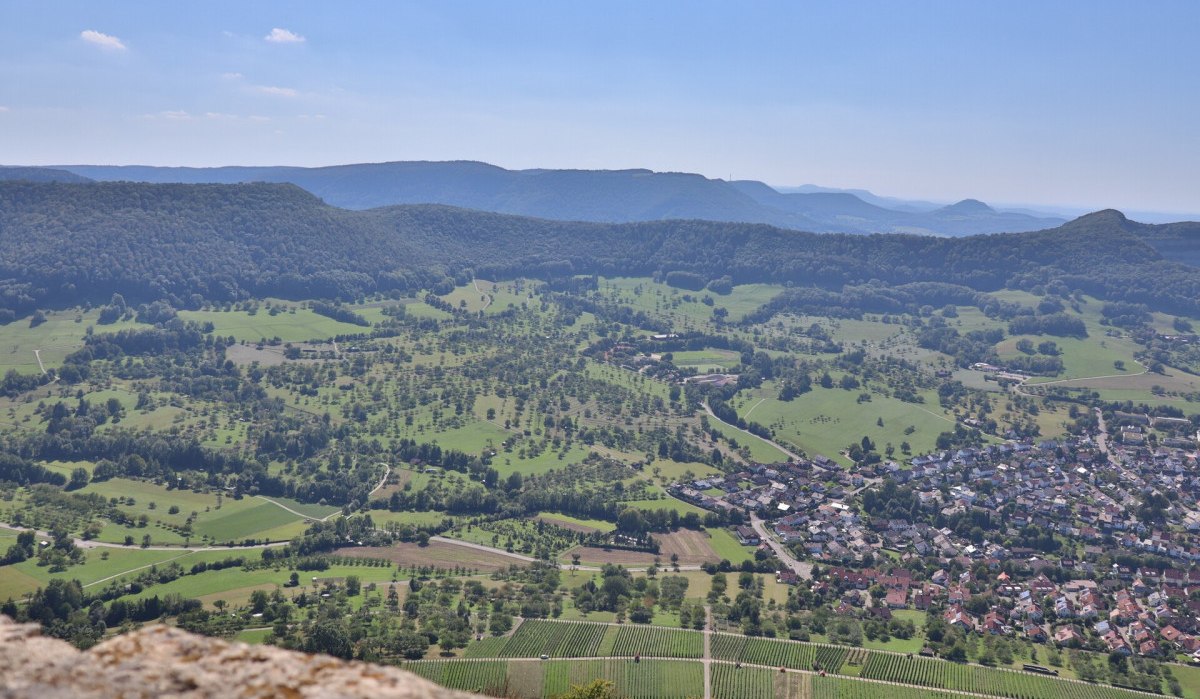 Panoramablick von der Burg Hohenneuffen über grüne Streuobstwiesen, Weinberge und die Stadt Neuffen im Tal., © hochgehberge