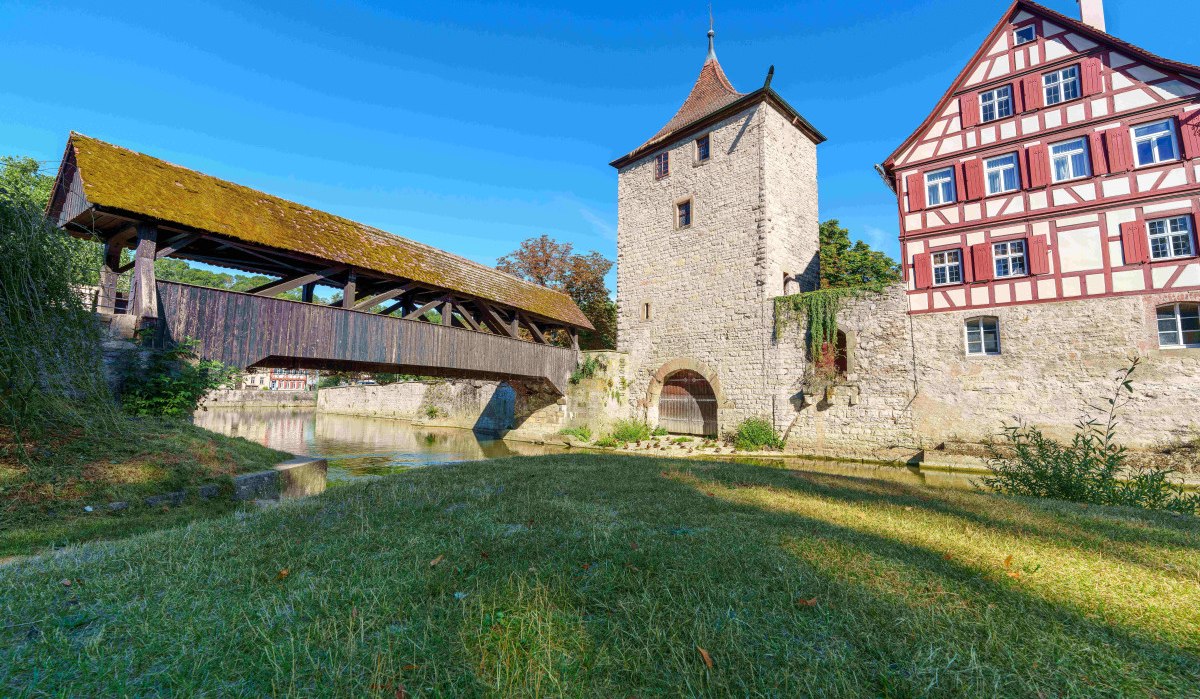 Der Sulferturm in Schwäbisch Hall mit einer überdachten Holzbrücke und einem Fachwerkhaus bei sonnigem Wetter., © Michael Kühneisen Der Sulferturm in Schwäbisch Hall mit einer überdachten Holzbrücke und einem Fachwerkhaus bei sonnigem Wetter., © Michael Kühneisen