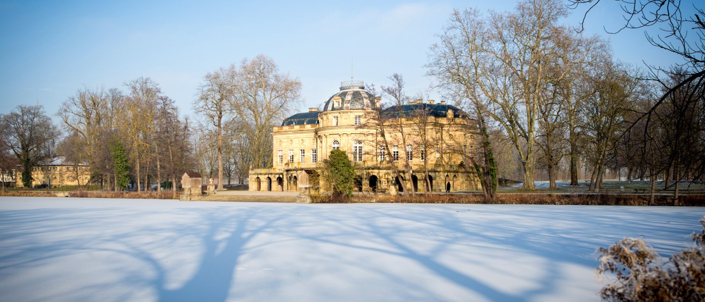 Seeschloss Monrepos im Winter, umgeben von kahlen Bäumen. Der See ist gefroren, und die Schatten der Bäume erstrecken sich über das Eis., © Tourismus & Events Ludwigsburg, Benjamin Stollenberg Seeschloss Monrepos im Winter, umgeben von kahlen Bäumen. Der See ist gefroren, und die Schatten der Bäume erstrecken sich über das Eis., © Tourismus & Events Ludwigsburg, Benjamin Stollenberg