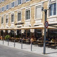Carls Brauhaus mit Stra&szlig;encaf&eacute;, Sonnenschirmen und G&auml;sten auf einer belebten Stra&szlig;e bei sonnigem Wetter., &copy; SMG, Sarah Schmid