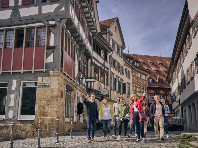 Eine Gruppe von Menschen spaziert durch eine Altstadt mit Fachwerkhäusern. Sie wirken fröhlich und interessiert., © Esslinger Stadtmarketing & Tourismus GmbH Eine Gruppe von Menschen spaziert durch eine Altstadt mit Fachwerkhäusern. Sie wirken fröhlich und interessiert., © Esslinger Stadtmarketing & Tourismus GmbH