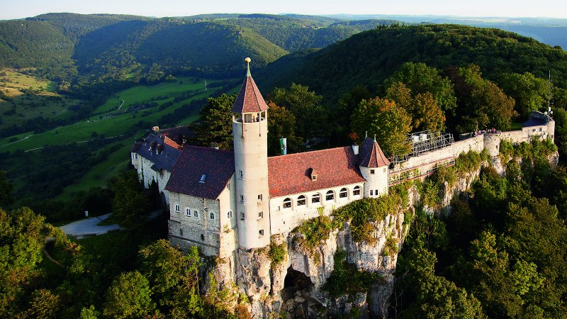 Die Burg Teck thront majestätisch auf einem bewaldeten Hügel, umgeben von grünen Tälern und Wäldern in der Ferne., © © Stuttgart-Marketing GmbH Die Burg Teck thront majestätisch auf einem bewaldeten Hügel, umgeben von grünen Tälern und Wäldern in der Ferne., © © Stuttgart-Marketing GmbH