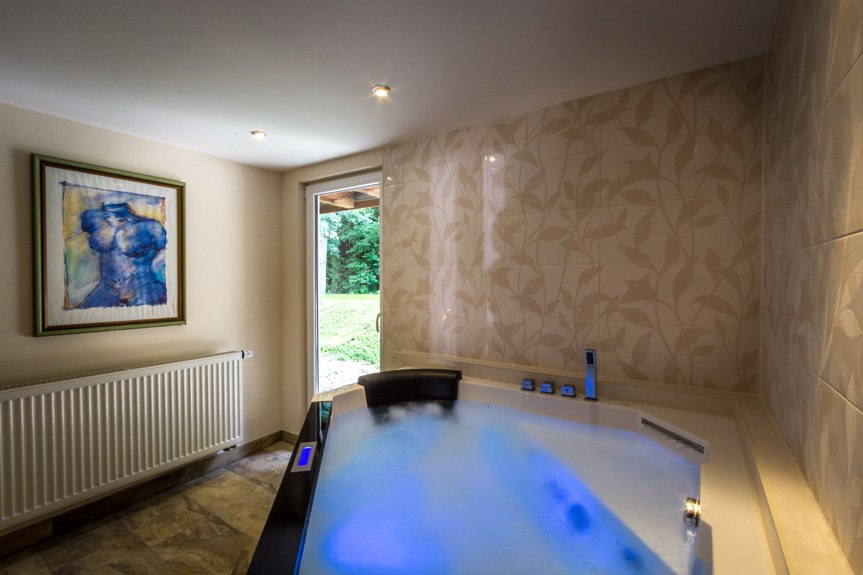 Whirlpool in einem Raum mit Kunstwerk an der Wand, Fliesen und Blick auf einen Garten., © Kulinarium an der Glems