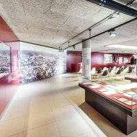 Modernes Museum mit Glasvitrinen, Sitzbereich und großem Wandbild. Helle Beleuchtung und rote Wände schaffen eine einladende Atmosphäre., © Stadt Göppingen