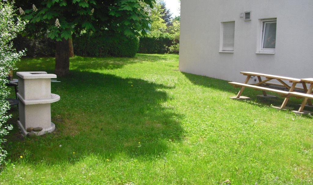 Grüne Wiese mit einem Baum, einem Grill und einem Picknicktisch neben einem weißen Gebäude., © TOMAS Grüne Wiese mit einem Baum, einem Grill und einem Picknicktisch neben einem weißen Gebäude., © TOMAS