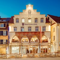 Abendansicht von „Der Andechser“ mit Hotel, beleuchteten Fenstern und Außengastronomie an einem Platz., © Tobias Fröhner Abendansicht von „Der Andechser“ mit Hotel, beleuchteten Fenstern und Außengastronomie an einem Platz., © Tobias Fröhner