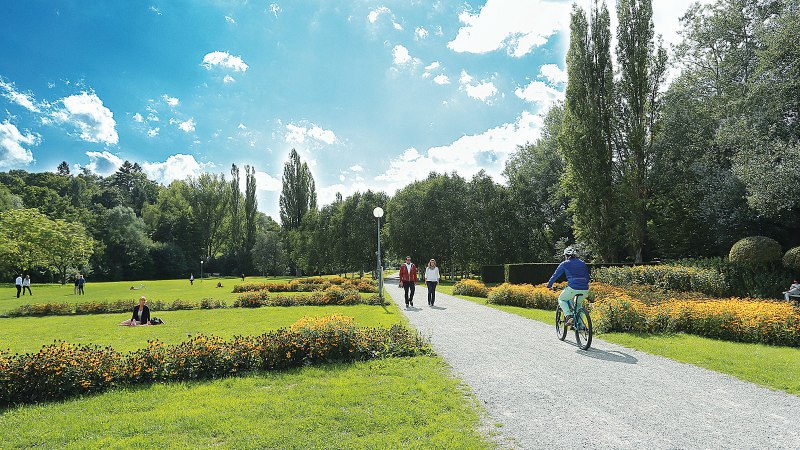 Grüne Wiese im Sommerhofenpark Sindelfingen mit Spaziergängern, Radfahrern und Blumenbeeten unter blauem Himmel., © Werberlinge Grüne Wiese im Sommerhofenpark Sindelfingen mit Spaziergängern, Radfahrern und Blumenbeeten unter blauem Himmel., © Werberlinge