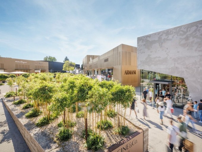 Moderne Einkaufsgeb&auml;ude in der Outletcity Metzingen mit Marken wie Armani. Menschen flanieren entlang der Gesch&auml;fte bei sonnigem Wetter., &copy; Schlienz-Tours GmbH &amp; Co.KG