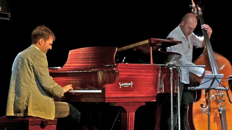 Ein Pianist spielt auf einem Fl&uuml;gel, w&auml;hrend ein Kontrabassist daneben steht. Beide Musiker sind in einem Jazzclub auf der B&uuml;hne., &copy; Foto Dieter Reinm&uuml;ller