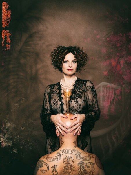 Frau in schwarzer Spitze mit Perlenkette hält einen goldenen Kelch auf einem tätowierten Kopf. Der Hintergrund ist künstlerisch gestaltet., © Veranstaltungsring Metzingen e.V. Frau in schwarzer Spitze mit Perlenkette hält einen goldenen Kelch auf einem tätowierten Kopf. Der Hintergrund ist künstlerisch gestaltet., © Veranstaltungsring Metzingen e.V.