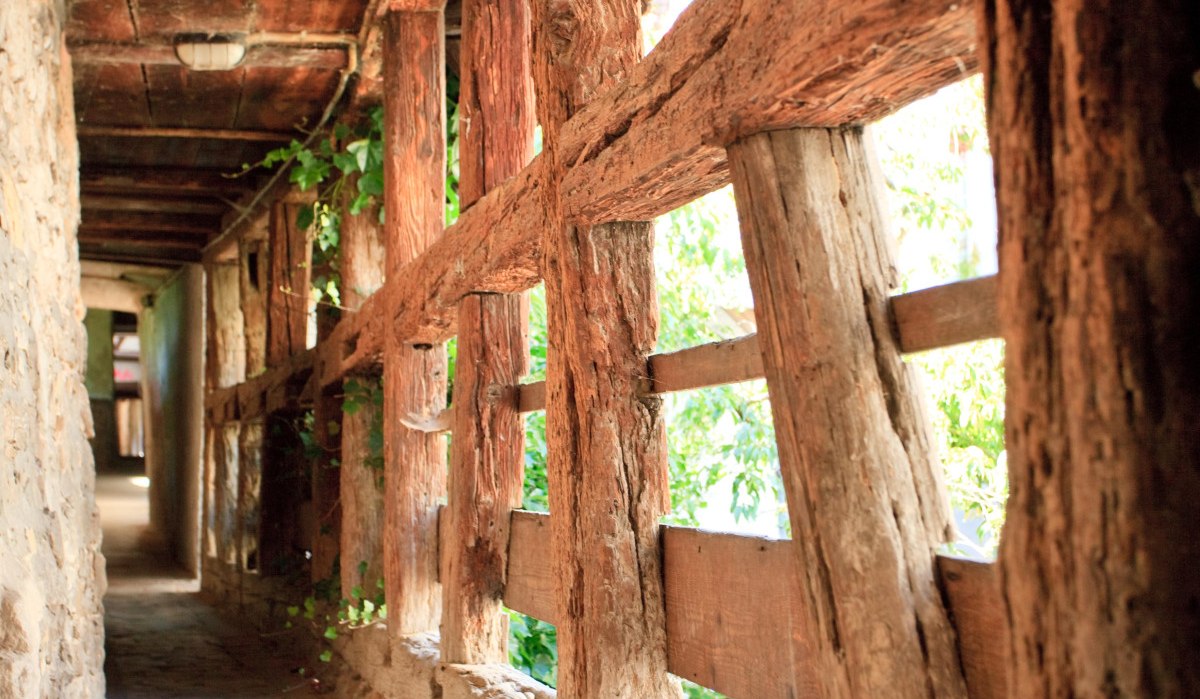 Schmaler Gang entlang einer alten Stadtmauer mit Holzbalken und Steinboden, von Sonnenlicht durchflutet., © Remstal Tourismus e.V.