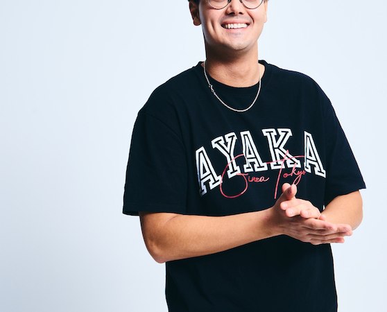 Ein Mann mit Brille und schwarzem T-Shirt mit 'AYAKA'-Aufdruck l&auml;chelt in die Kamera. Er steht vor einem neutralen, hellen Hintergrund., &copy; Osiander Vertriebsgesellschaft mbH & Co. KG